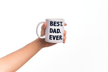 Hand of caucasian young man holding cup of coffee with best dad ever message over isolated white background