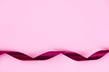 decorative satin Burgundy ribbon on a pink background