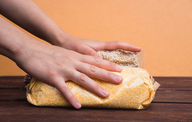 Hold food in hands. Buckwheat, corn, and barley. Raw porridge in a package.