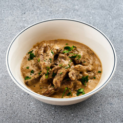 Sliced ​​beef in a sauce in a white plate.