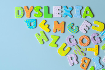 Word Dyslexia written of wood letters and scattered letters below on blue background