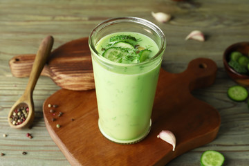 Glass with cold cucumber soup on table