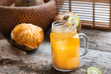 exotic fruit juice from Bel fruit or wooden Apple called in India Bel Ka Sharbat. cold fruit drink with ice and Bel fruit slices on wooden rustic background. natural detox. vitamins for immunity