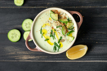 Pot with cold cucumber soup on table