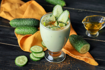 Glass with cold cucumber soup on table