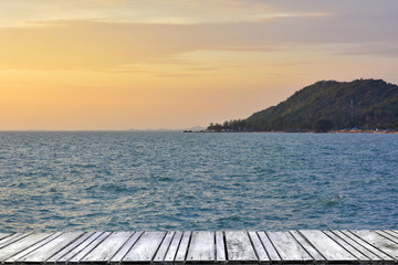 Naklejka premium Sunset at sea and old wooden bridgeมPerspective view of wooden pier on the sea at sunset with perfectly specular reflection,wooden retro deck and sunrise or sunset sky/ Summer holidays background.