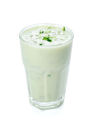 Glass with cold cucumber soup on white background