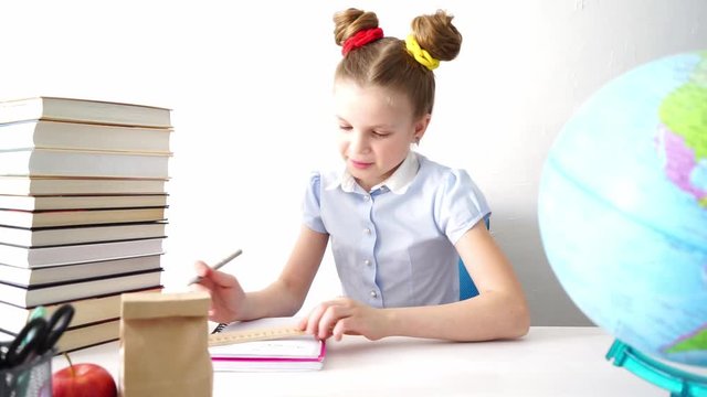 Back to school: A schoolgirl sits at her desk and takes notes in a notebook.