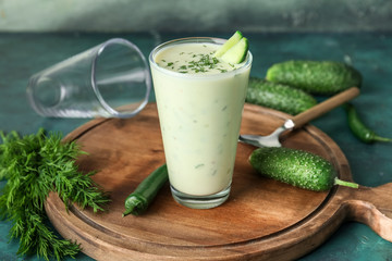 Glass with cold cucumber soup on table