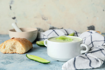 Pot with cold cucumber soup on table
