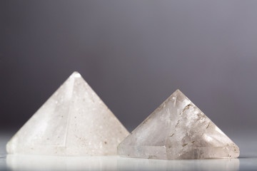Two natural rock crystal pyramids against a dark background