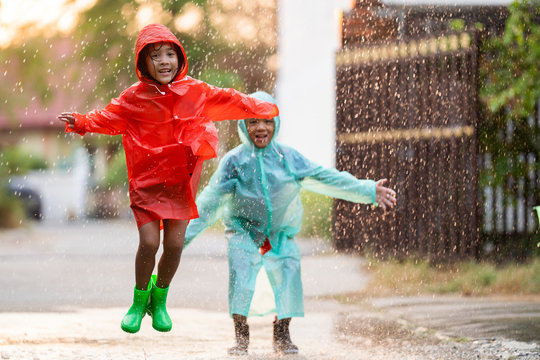 Asian Children Playing In The Rain Are Happy.They Are Jumping