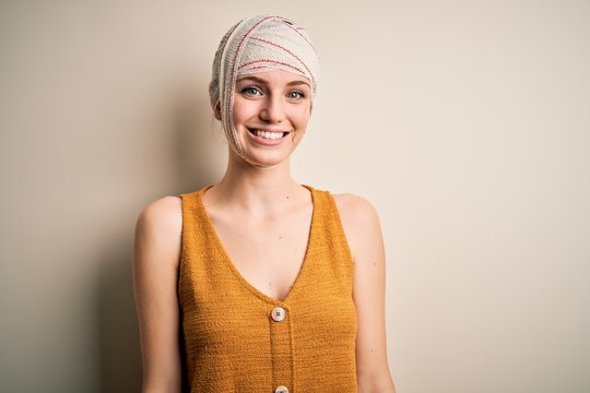 Young beautiful redhead woman injured for accident wearing bandage on head with a happy and cool smile on face. Lucky person.