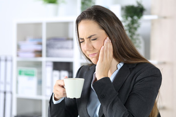 Executive with toothache holding coffee at office