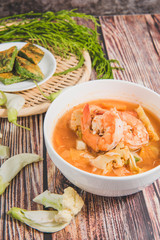 Mixed shrimp curry in a white bowl on a wooden background.