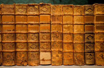 Selective focus on bookshelf with antique leather covers, printed at 18th century. Old books of a library or bookstore