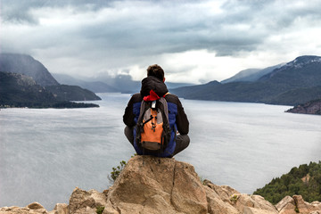 Boy with his back to a mountainous lake