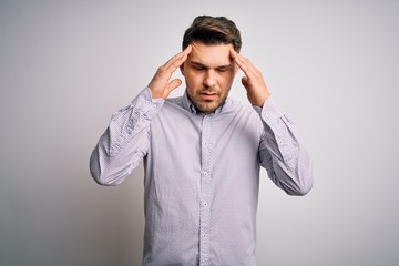 Young business man with blue eyes standing over isolated background with hand on head for pain in head because stress. Suffering migraine.