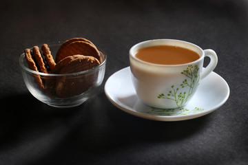 A ceramic cup of red tea served with butter cookies biscuit on the black background selective focus with on subject and  surface.  Isolated. 