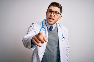 Young doctor man with blue eyes wearing medical coat and stethoscope over isolated background pointing displeased and frustrated to the camera, angry and furious with you