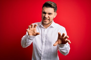 Young business man with blue eyes wearing elegant shirt standing over red isolated background...