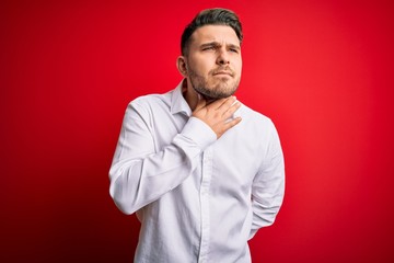 Obraz premium Young business man with blue eyes wearing elegant shirt standing over red isolated background Touching painful neck, sore throat for flu, clod and infection