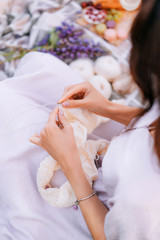 Fototapeta na wymiar Hands close-up knitting on knitting needles, white milk wool knit during a picnic. Needlework in the garden.