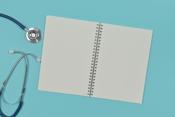 Open notebook with stethoscope on blue background.