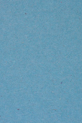 The surface of a sheet of blue or azure gray cardboard. Rough natural paper texture with cellulose fibers. Background or wallpaper. View from above. Vertical shot. Macro