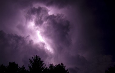 purple clouds with lightning strike against cloudy night sky