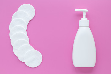 Cosmetic bottle and cotton pads on a pink background. Copy space, empty place. Facial toner, makeup...