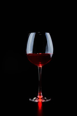 A large glass of red wine on a black background