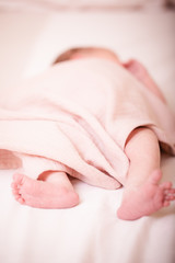 Close up picture of newborn baby feet. Sleeping newborn baby on a light blanket.