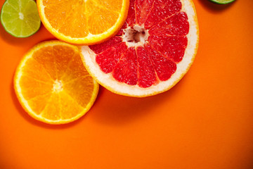 Fresh slices of citrus on the orange background. View from above. Place for text.