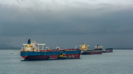 Fototapeta premium Loading anchored oil supertanker via a ship-to-ship oil transfer (STS) from raid tanker