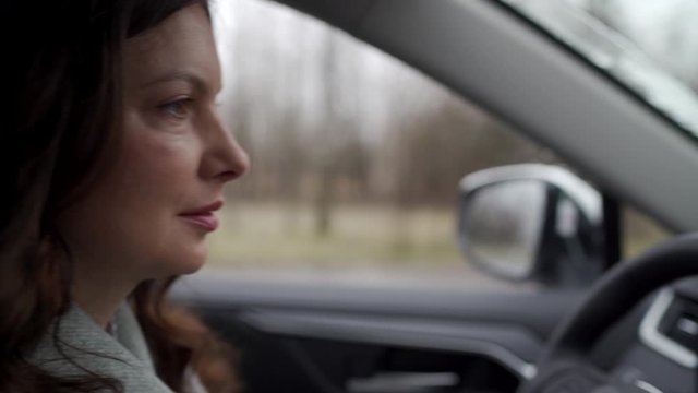 Brunette woman driver behind the steering wheel driving her crossover suv car