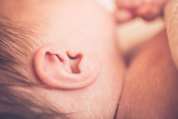 Newborn baby boy lying on bed, sleeping, close up. Healthy newborn baby sleeping, showing close up of ear and side of babies head.