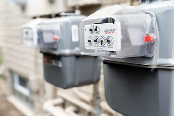 Row of gray natural gas meters at an apartment complex