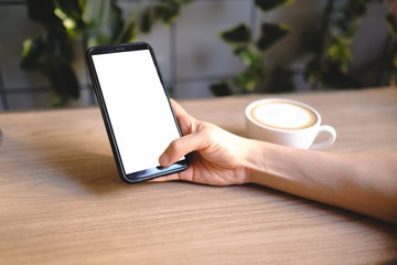 Close up of woman using blank cell phone order products for shopping online within the cafe.