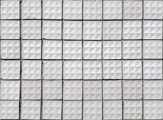 Old textured square white ceramic tiles.