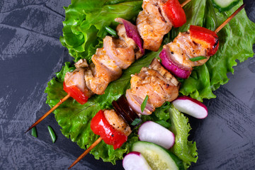 Shashlik made of chicken and vegetables on wooden skewers on the grey table