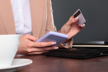 A woman is sitting at a Desk and shopping online. An unrecognizable photo. Copy of the space.