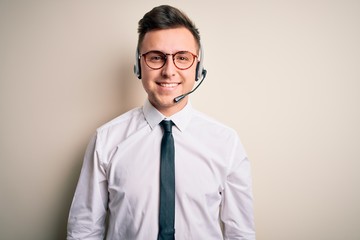 Young handsome caucasian business man wearing call center headset at customer service with a happy and cool smile on face. Lucky person.