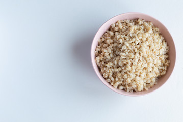 National Russian pearl barley porridge in a pink bowl on a white background