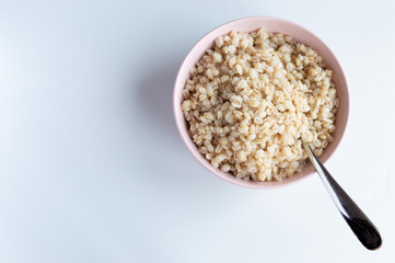 National Russian pearl barley porridge in a pink bowl on a white background