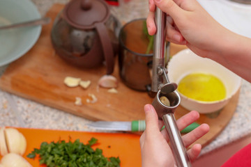 Girl crushes garlic. Cooking at home.