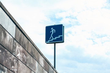 Road sign pedestrian underpass against the blue sky with fluffy clouds