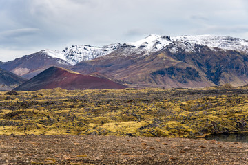 Rugged volcanic landscape with snow-capped mountains in background in Iceland on a cloudy autumn day. Natural Background.