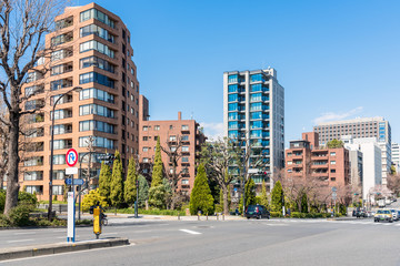 Modern apartment buildings on a sunny spring day. An intersection with traffic lights is in foreground. Tokyo, Japan.