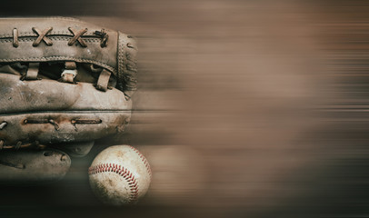 Old used baseball glove with ball on motion blur background, copy space.